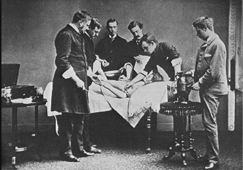 File:Male Doctors Looking Down on Female Patient.png